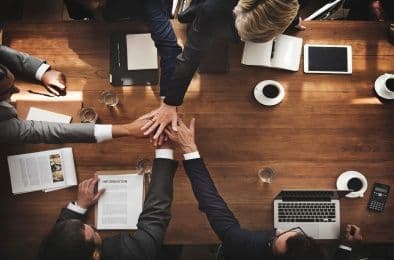 An image of people gently placing their hands on top of each other's in a gesture of support and teamwork.